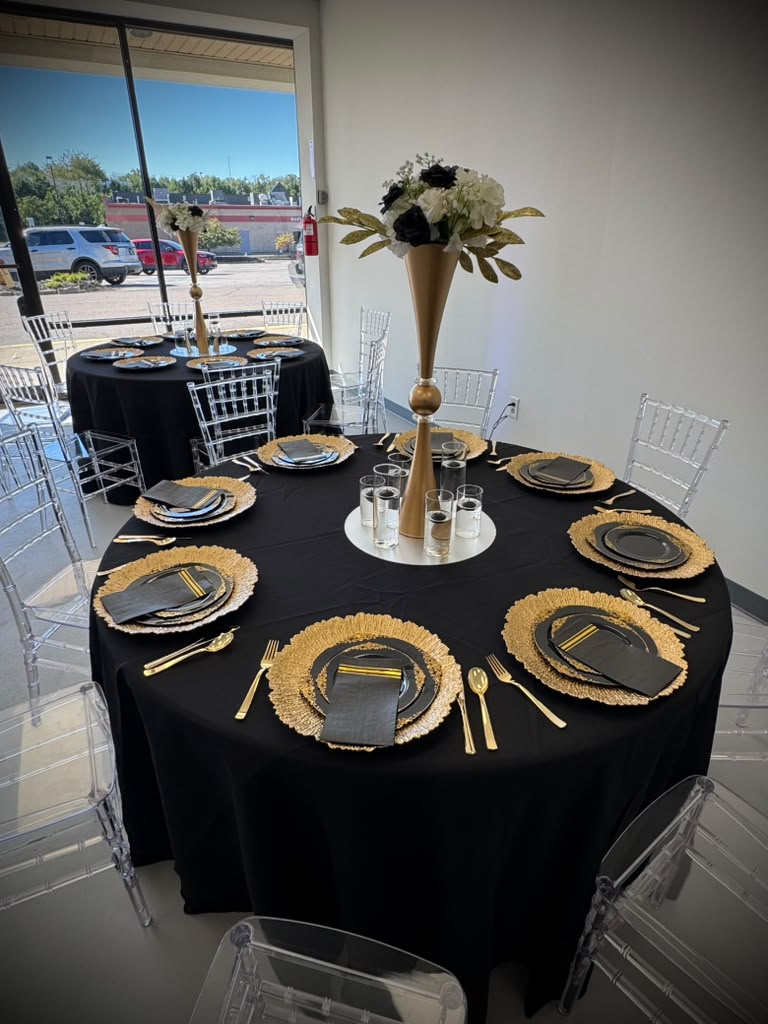 Round guest tables with gold place settings and clear chairs